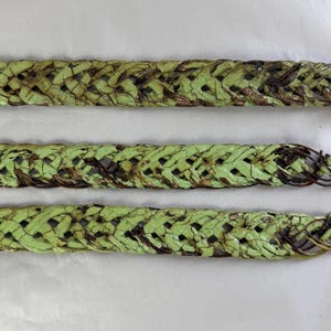 May include: Three parallel lengths of braided rope featuring a distressed finish with a light green painted surface over a dark brown base. The braided texture is visible throughout each strand, with frayed ends showing the dark brown core material.
