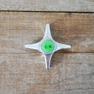 May include: A silver metal four-pointed star-shaped valve with a green round center that says "C.W."