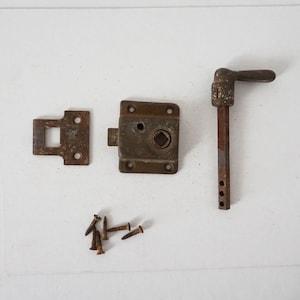 May include: A set of rusty metal hardware for a door or window. The set includes a handle, a latch, a strike plate, and screws.