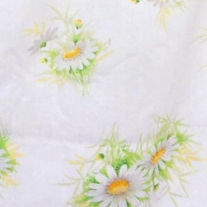 May include: White fabric with a repeating pattern of daisies. The daisies have white petals and yellow centers, with green and yellow stems and leaves. The fabric is likely a sheet or pillowcase.