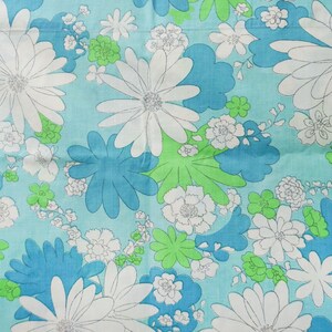 May include: A fabric with a floral pattern featuring large white daisies with gray outlines, blue and green stylized flowers, and smaller white blossoms on a light blue background. The design is reminiscent of a vintage aesthetic.