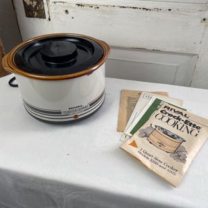 May include: A vintage Rival Crock-Ette slow cooker, cream-colored with brown accents and a black lid. The appliance has a 1-quart capacity and includes a booklet titled "Rival Crock-Ette Cooking".