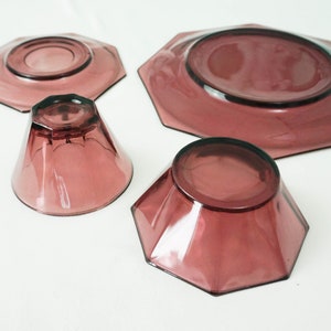 May include: Set of four purple glass dishes, including two small bowls, a saucer, and a larger plate. All dishes have a geometric octagonal shape.