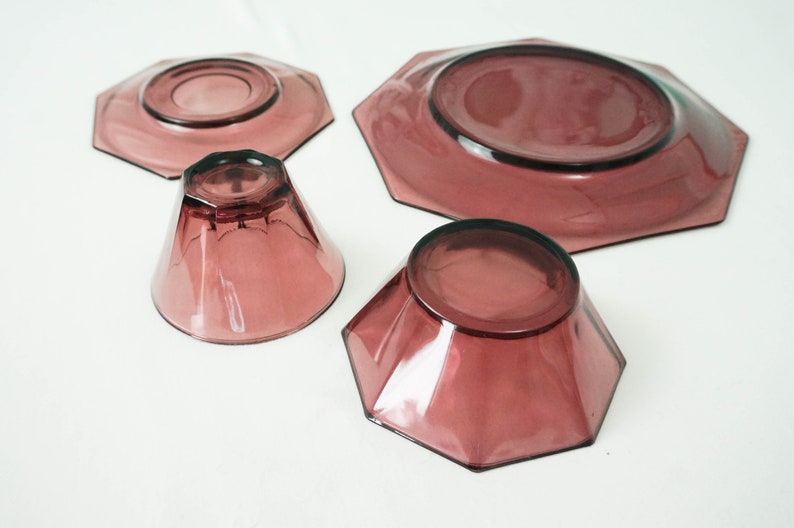 May include: Set of four purple glass dishes, including two small bowls, a saucer, and a larger plate. All dishes have a geometric octagonal shape.