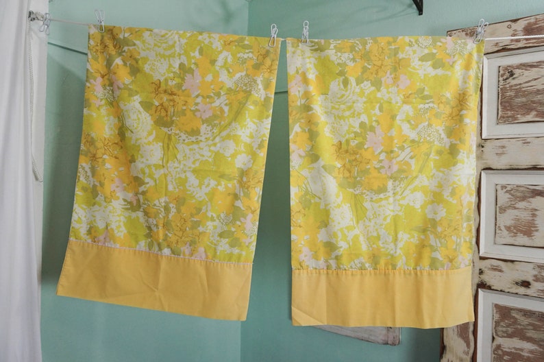 Pode incluir: Um par de fronhas amarelas com flores e uma borda amarela s&oacute;lida. As fronhas t&ecirc;m um padr&atilde;o floral vintage com flores amarelas, verdes e rosas.