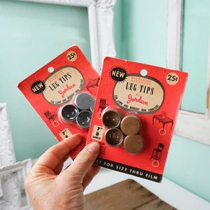 May include: Two packages of furniture leg tips, one with black tips and one with gold tips. Both packages are red and white and say "NEW" and "LEG TIPS by Jordan".