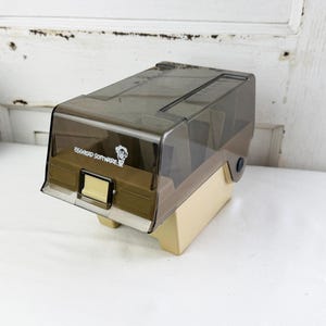 May include: A vintage beige and translucent brown plastic media storage case with a hinged lid. The front features a small cream-colored latch and the printed text Egghead Software with a small cartoon character logo on the front panel.