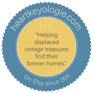 Pode incluir: Um logotipo circular com uma borda azul e um centro amarelo. O texto "heartkeyologie.com" est&aacute; em arco na parte superior. No interior, l&ecirc;-se "HK" e "Helping displaced vintage treasures find their forever homes." A parte inferior diz "On Etsy since 2011."
