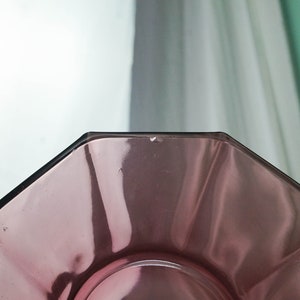 May include: A clear, octagonal glass plate with a slight purple tint. The plate is empty and has a smooth, reflective surface.