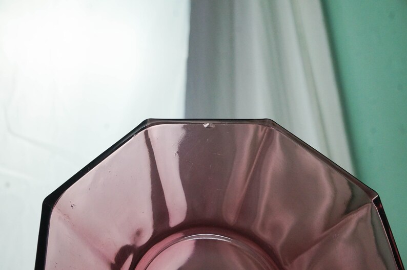 May include: A clear, octagonal glass plate with a slight purple tint. The plate is empty and has a smooth, reflective surface.