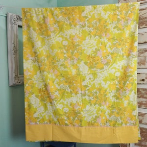 Pode incluir: Um len&ccedil;ol de cama com padr&atilde;o floral amarelo e verde com uma borda amarela. O len&ccedil;ol est&aacute; pendurado em um varal.