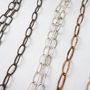 May include: Four different chain styles, including a brass chain, a gold chain, a silver chain, and a white chain. The chains are all oval-shaped links.