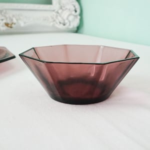 May include: A purple glass bowl with an octagonal shape. The bowl is sitting on a white surface.