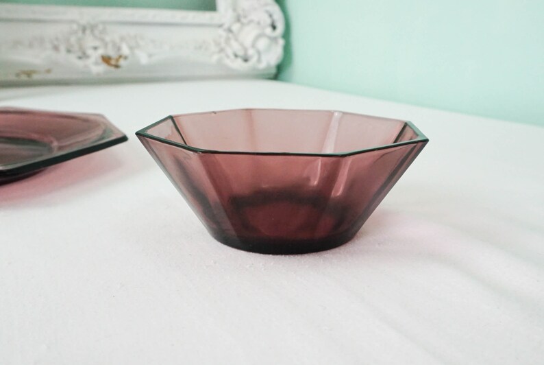 May include: A purple glass bowl with an octagonal shape. The bowl is sitting on a white surface.