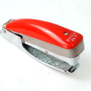 May include: A red and silver stapler with the text "BATES 88P" on the top.