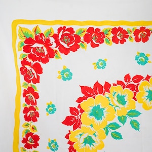 May include: White tablecloth with a vibrant floral pattern. The design features large red and yellow flowers with green leaves and turquoise centers, set against a white background. A yellow border frames the edges, creating a cheerful, vintage aesthetic.