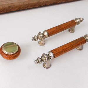 May include: Two wooden cabinet knobs with silver accents and a single round wooden knob with a brass center.