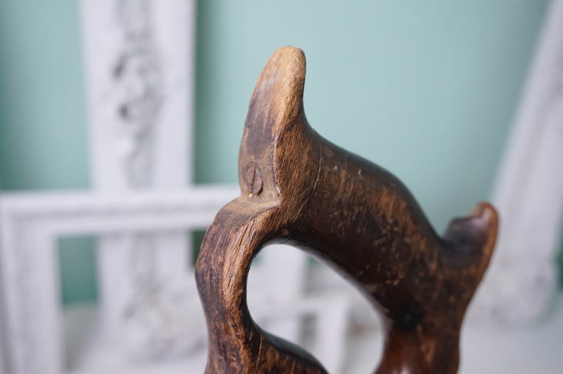 May include: Close-up of a wooden hand plane with a dark brown finish. The handle is shaped like a bird's head with a small hole in the top.