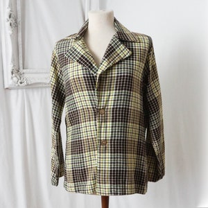 May include: A long-sleeved plaid jacket with a brown, yellow, and white plaid pattern. The jacket has a collar and a button closure.