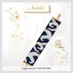 May include: A wide peyote stitch bracelet featuring a dark navy blue background with a repeating white and light blue wave-like pattern. The bracelet has gold-tone metal end bars and a lobster clasp. The text Natelier is visible above.