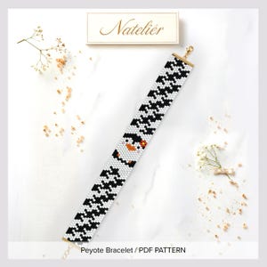 May include: A beaded bracelet featuring a repeating black and white geometric pattern with a central penguin graphic. The bracelet includes a gold-toned lobster clasp and a small gold-toned chain extender. The text Natelier is visible above.