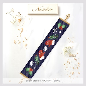 May include: A dark blue loom bracelet featuring a repeating holiday pattern of red mittens, green pine branches, and white snowflakes. The bracelet has gold-toned metal end bars and a lobster claw clasp. Above the bracelet is a label reading Nateliér.