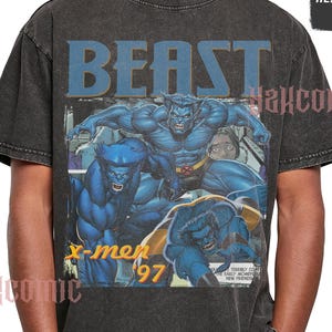 May include: A charcoal grey acid-wash t-shirt featuring a graphic print of the blue-furred character Beast from X-Men '97. The design includes the word BEAST in large blue letters at the top, the text x-men '97 in yellow, and comic book panels.