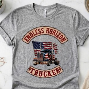 May include: A heather grey short-sleeved t-shirt featuring a graphic print of a semi-truck overlaid with an American flag. The design includes the text ENDLESS HORIZON TRUCKER in a curved banner style, with a distressed, vintage-inspired aesthetic.