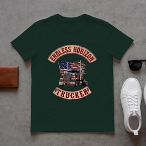 May include: A dark green short-sleeved t-shirt featuring a graphic of a semi-truck in front of an American flag, with the text ENDLESS HORIZON TRUCKER in a distressed red font. The shirt is displayed alongside a brown leather wallet and sunglasses.