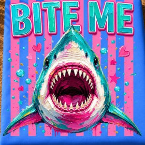 May include: A digital art print featuring a shark with an open mouth and sharp teeth, centered over a blue and pink striped background. The text BITE ME appears in large, textured teal letters at the top, surrounded by small pink hearts and stars.