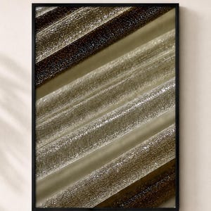 Op de afbeelding: Een ingelijste wandkunstprint met een macro-opname van diagonale, parallelle lijnen in tinten donkerbruin, taupe en doorschijnend wit. De compositie toont een herhalend patroon van getextureerde, cilindrische vormen met een glanzende afwerking.