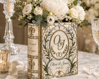 May include: A rectangular, book-shaped vase with a stained-glass style finish in cream and gold. The front features the text O&J, Olivia & James, 11.08.25, and Forever Begins, decorated with lily of the valley illustrations and a bouquet of white flowers.