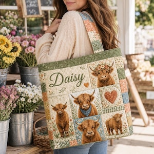 May include: A quilted tote bag featuring a patchwork design with illustrations of Highland cattle, floral accents, and a heart shape. The name Daisy is embroidered in green script on the front panel. The bag has a wide shoulder strap.