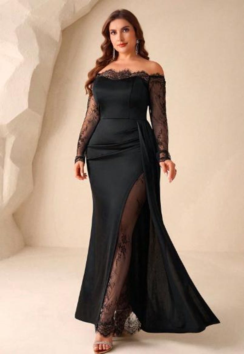 May include: A floor-length black gown featuring an off-the-shoulder neckline with delicate lace trim, long sheer lace sleeves, and a fitted bodice. The skirt includes a high side slit that reveals a sheer lace panel underneath the satin fabric.
