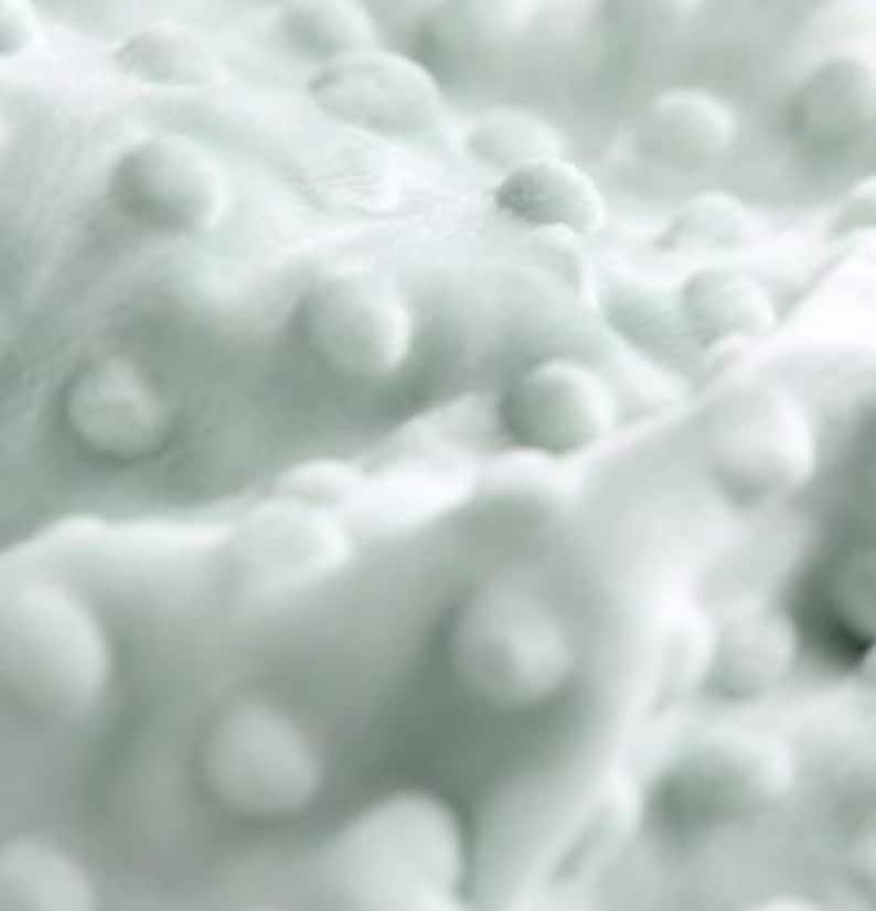 May include: A soft, light mint green fabric featuring a raised, textured dot pattern across the entire surface. The material has a plush, velvety appearance with consistent, evenly spaced circular bumps that create a tactile, three-dimensional effect.