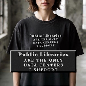 Może przedstawiać: Czarny t-shirt z krótkim rękawem z białym nadrukiem na klatce piersiowej o treści: Public Libraries ARE THE ONLY DATA CENTERS I SUPPORT. Koszulka posiada okrągły dekolt oraz standardowy krój z wyraźnym i czytelnym napisem graficznym.