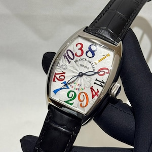 Könnte beinhalten: Eine silberne Franck Muller Crazy Hours Uhr mit weißem Zifferblatt und bunten Ziffern. Die Uhr hat ein schwarzes Lederarmband und die Worte "Crazy or Dreams" sind auf dem Zifferblatt aufgedruckt.