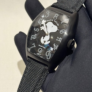 Könnte beinhalten: Schwarze Franck Muller Uhr mit Snoopy-Design auf dem Zifferblatt. Die Uhr hat ein schwarzes Armband und ein schwarzes Gehäuse. Das Zifferblatt zeigt weiße Ziffern und die Wörter "FRANCK MULLER" und "BAMFORD".