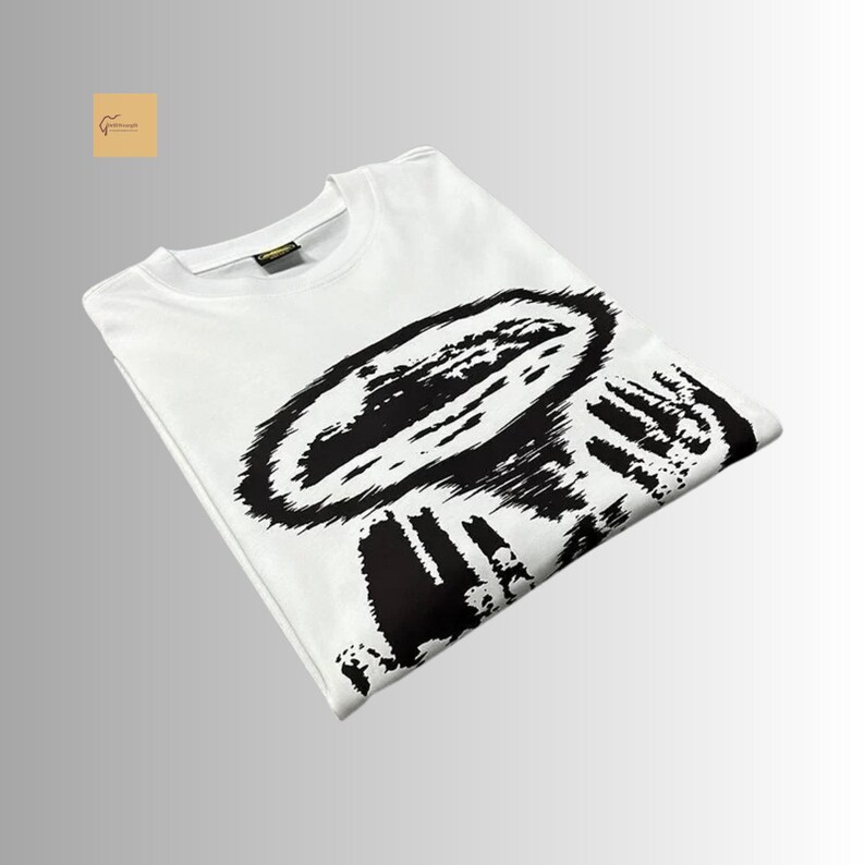 May include: A white short-sleeved t-shirt featuring a large, bold black graphic print on the front. The design consists of a textured, abstract circular shape with radiating lines, creating a high-contrast visual effect on the fabric.