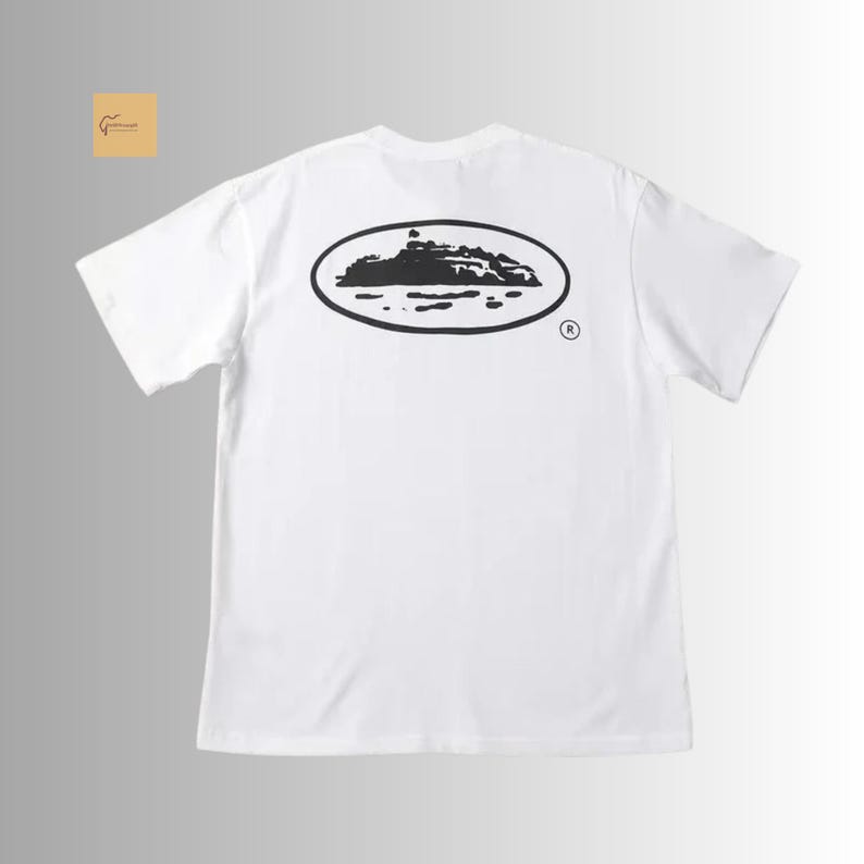 May include: A white short-sleeve t-shirt featuring a black graphic on the back. The graphic consists of an oval outline containing a silhouette of a landmass or island surrounded by water, with a small registered trademark symbol to the right.
