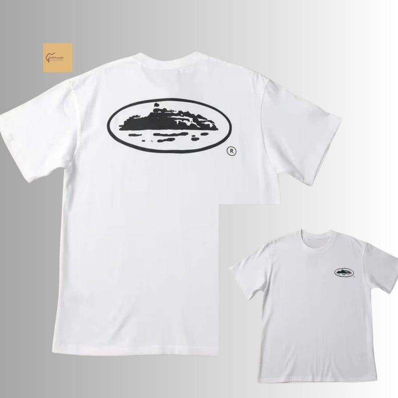 May include: A white short-sleeve t-shirt featuring a large black oval graphic on the back containing a silhouette of an island or landmass. A smaller version of the same black oval island graphic is positioned on the left chest area of the shirt.