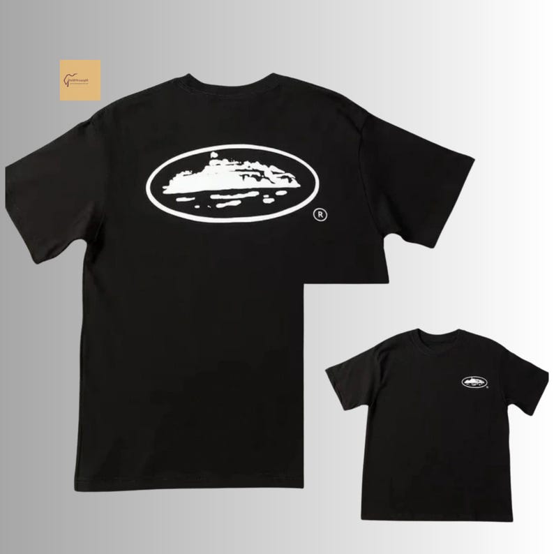 May include: A black short-sleeve t-shirt featuring a large white oval graphic on the back containing a silhouette of a cruise ship. A smaller version of the same white oval cruise ship graphic is positioned on the front left chest area of the shirt.