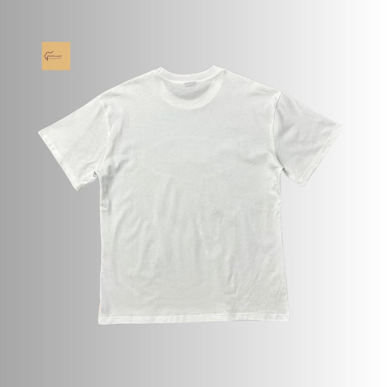 May include: A plain white short-sleeved t-shirt with a crew neckline. The garment features a solid white color throughout, with a small square logo in the top left corner containing a brown line drawing of a guitar and the text GuitarCraft.