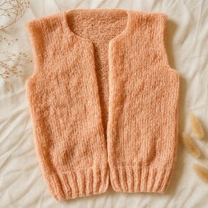 May include: A peach-colored, open-front knitted vest. The sleeveless garment features a rounded neckline and ribbed hem. The soft, textured knitwear is displayed on a neutral background, showcasing its delicate construction and color.