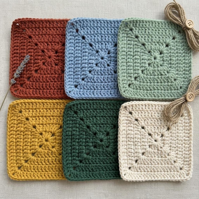 Peut inclure: Ensemble de six dessous de verre carr&eacute;s au crochet, de couleurs rouille, bleu clair, vert sauge, jaune moutarde, vert for&ecirc;t et cr&egrave;me. Chaque dessous de verre pr&eacute;sente un motif central en &eacute;toile. Ficelle naturelle et bouton inclus.