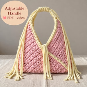 May include: A pink crocheted handbag featuring a light yellow adjustable handle and long fringe accents. The bag has a textured stitch pattern and includes a circular graphic with the text Adjustable Handle PDF + video.