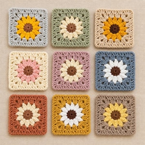 May include: Nine crocheted squares with sunflower designs in various colors. The squares feature yellow, white, pink, and brown sunflowers on backgrounds of gray, green, beige, purple, blue, orange, and gold.