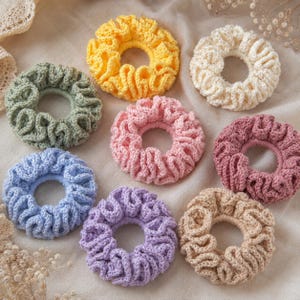 May include: A collection of eight handmade crochet scrunchies in various colors. The scrunchies are in shades of yellow, green, pink, blue, purple, beige, and cream. Each scrunchie is round with a ruffled texture, perfect for accessorizing.