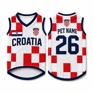 May include: A sleeveless mesh pet jersey featuring a red and white checkered pattern. The front displays the text CROATIA, a small Croatian flag, and a crest. The back shows the text PET NAME above the large navy blue number 26 and a crest.