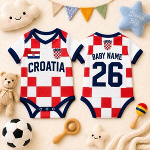 May include: Two baby bodysuits featuring a red and white checkered pattern inspired by the Croatian flag. The front displays the text CROATIA and a crest, while the back shows the text BABY NAME and the number 26 in dark blue lettering.